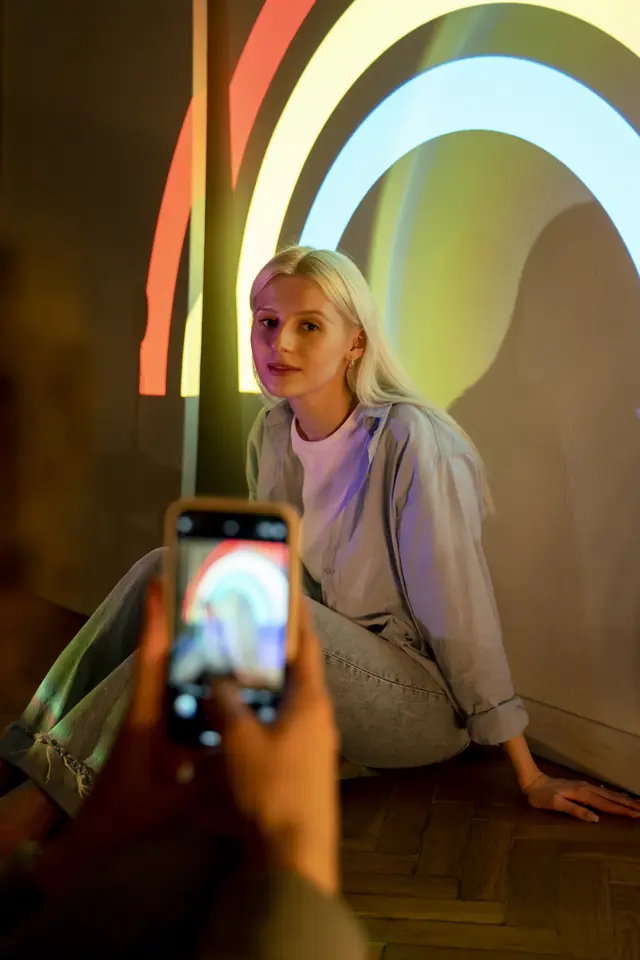 Creatorin wird im Licht eines Filmprojektors mit dem Smartphone fotografiert